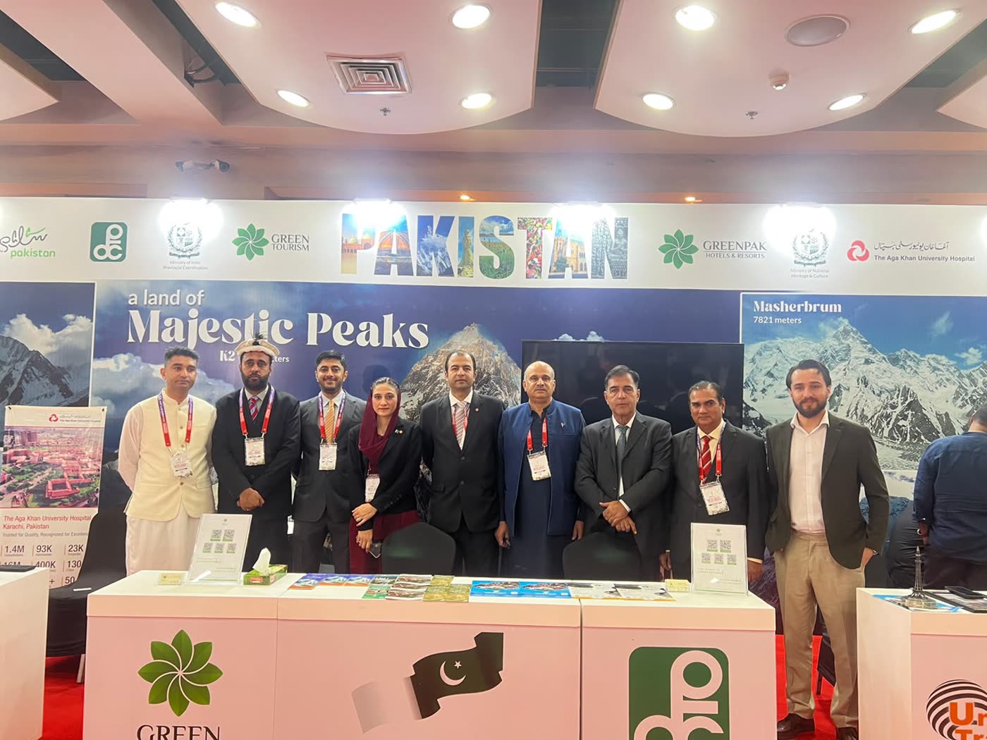 Pakistan delegation standing at the national pavilion under the banner A Land of Majestic Peaks